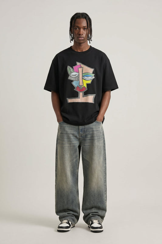 Person wearing a black t-shirt with colorful design and light blue jeans on a white background