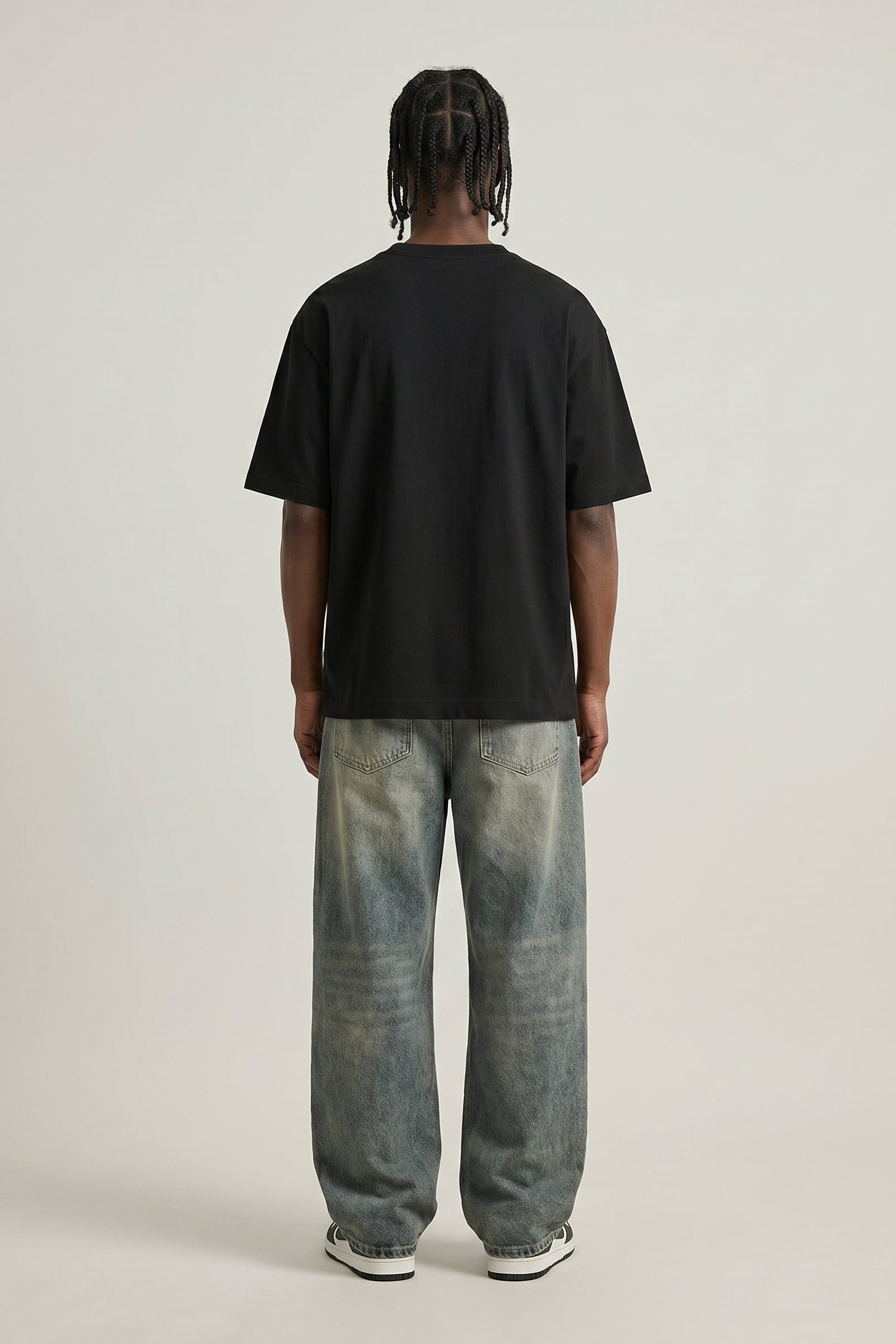 Person wearing a black t-shirt and light blue jeans on a plain background