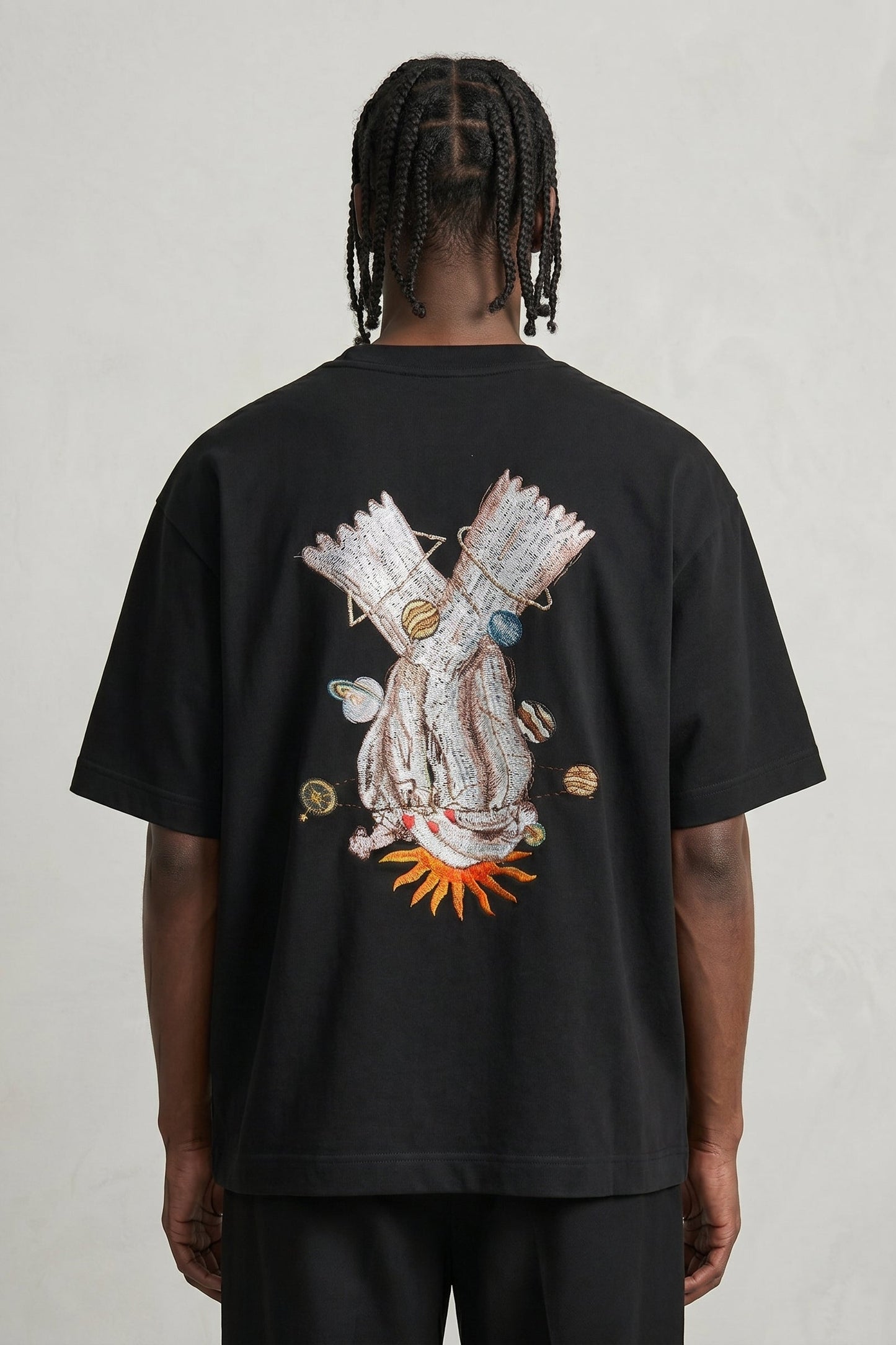 Person wearing a black t-shirt with a colorful graphic on the back against a plain background