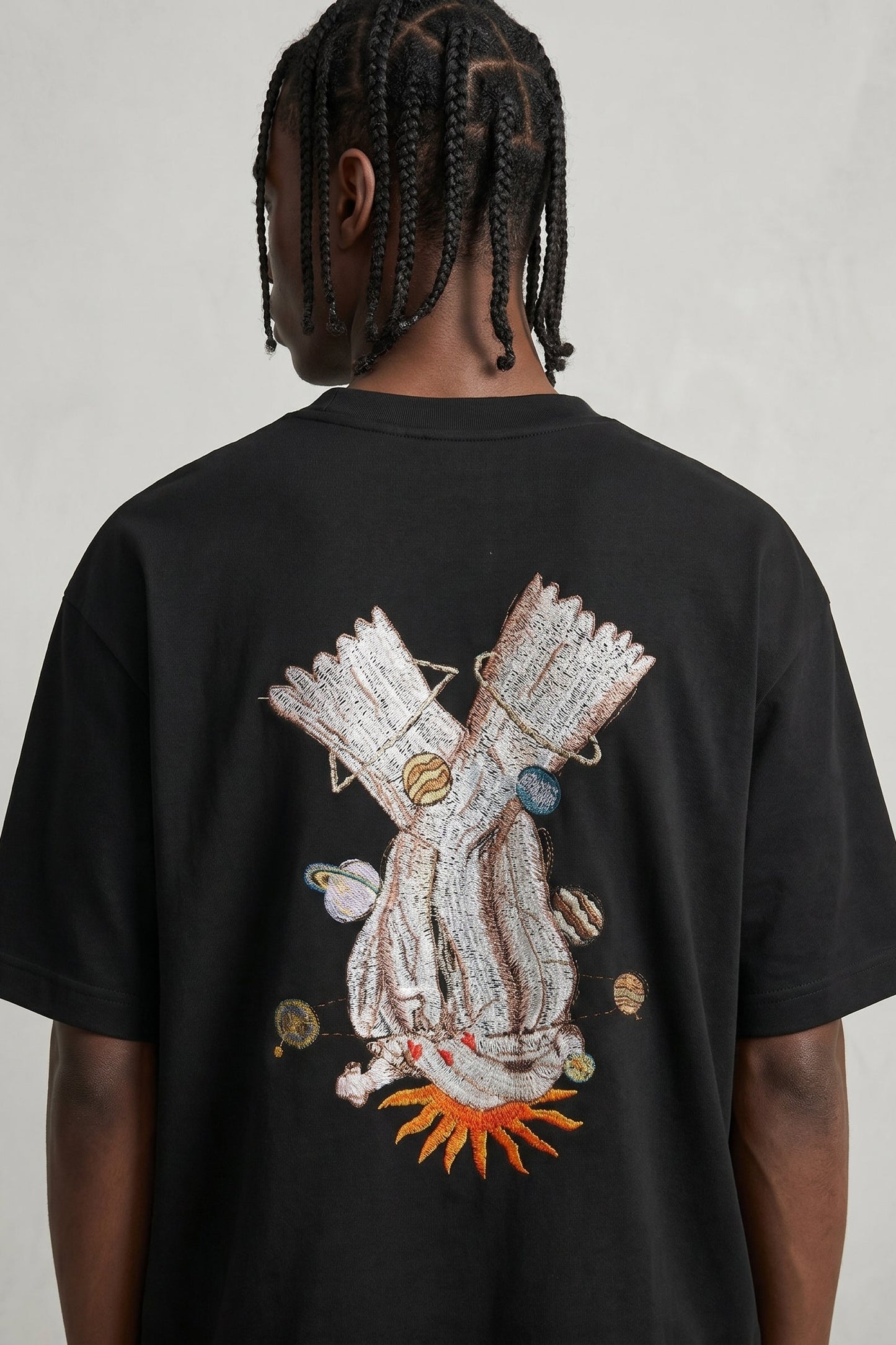 Person wearing a black t-shirt with a colorful graphic design on the back against a plain background
