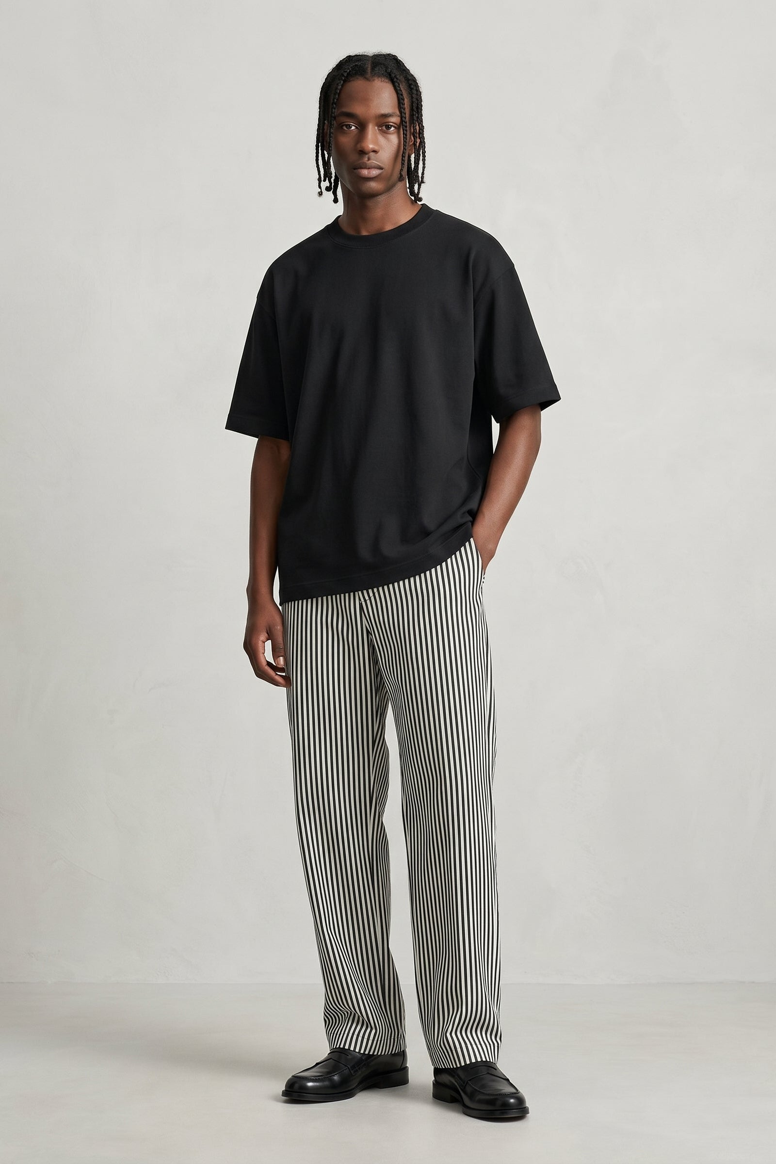Person wearing a black t-shirt and striped pants on a plain background