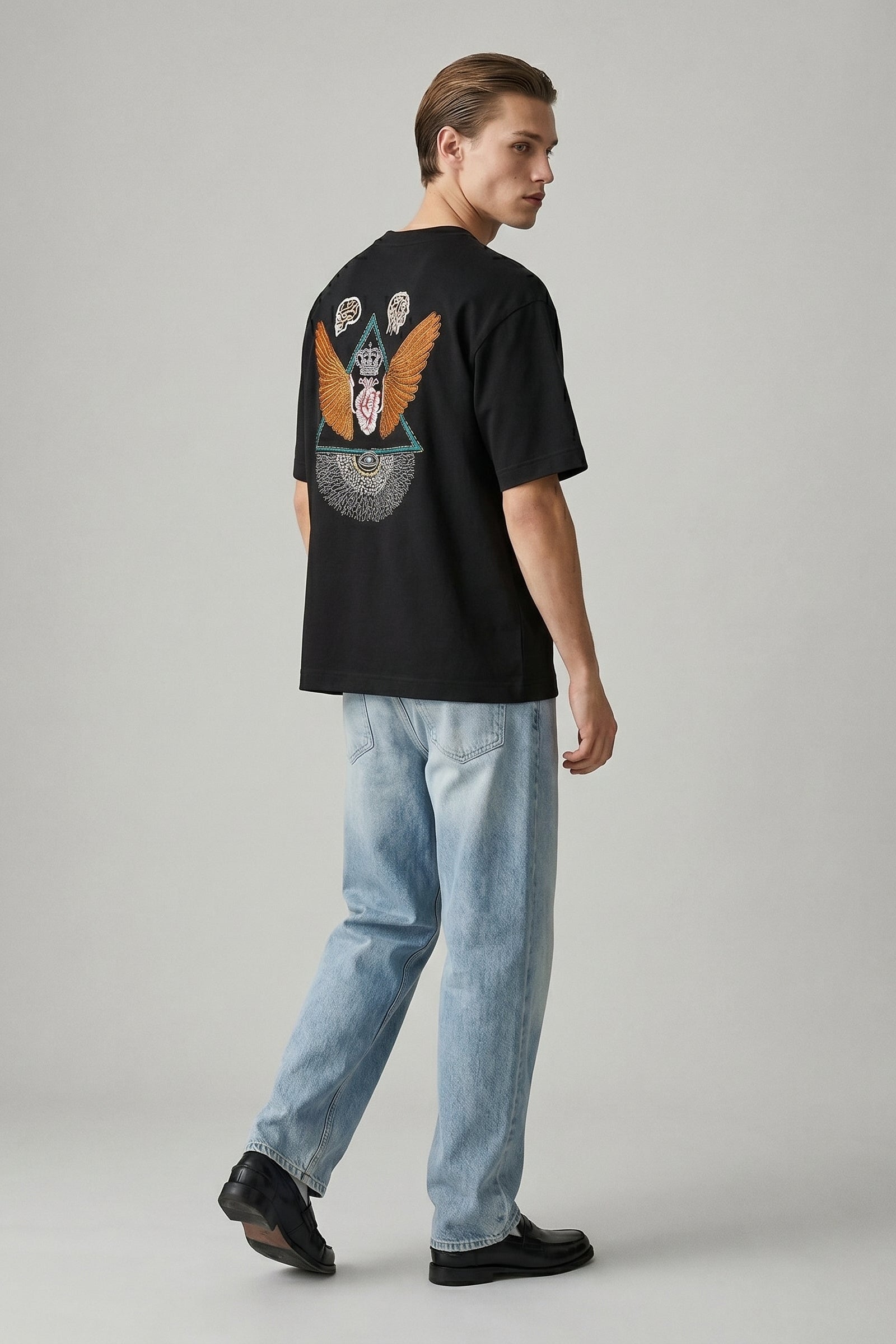 Person wearing a black t-shirt with a colorful design on the back, standing against a plain background.