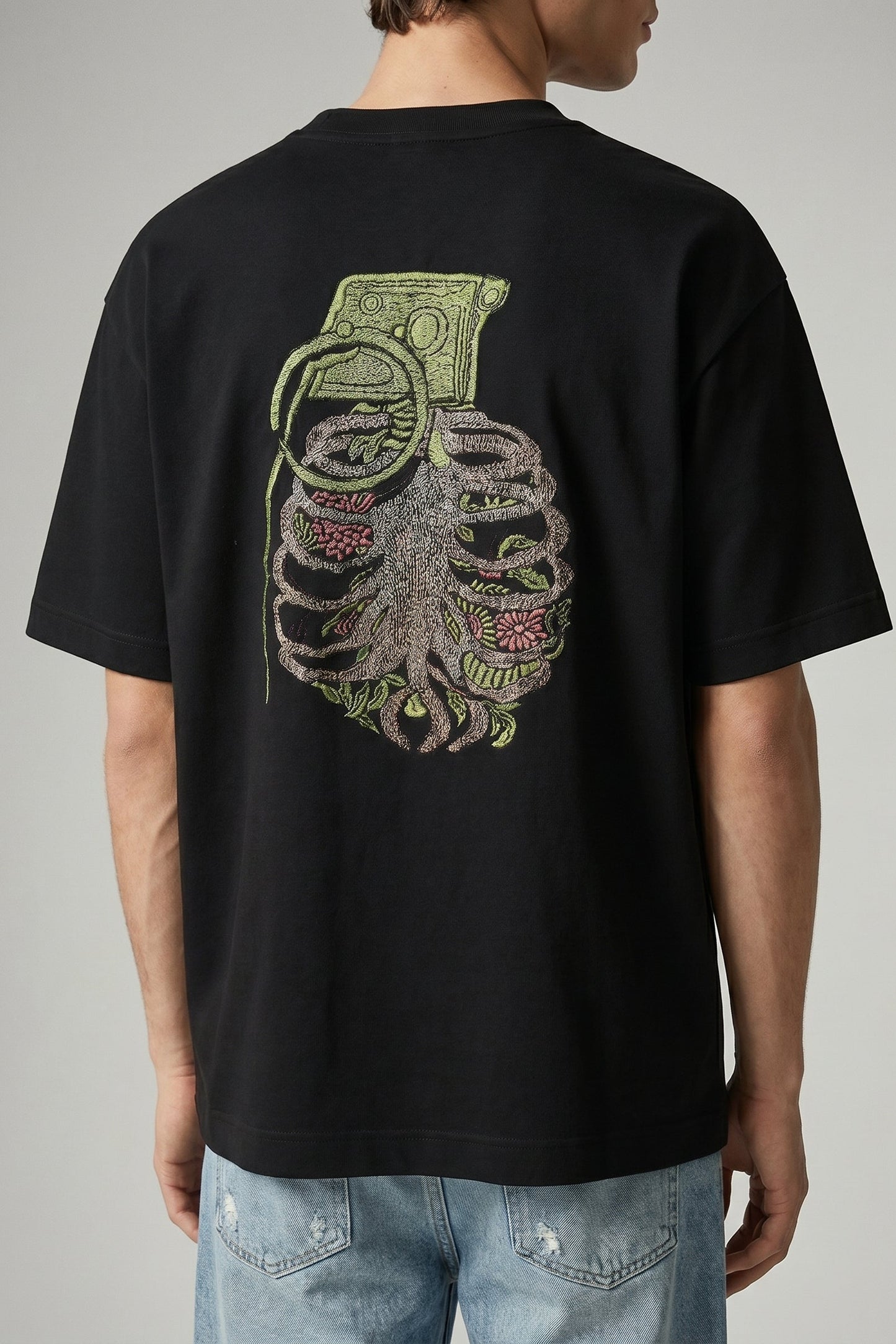 Black t-shirt with a graphic design on the back, worn by a person.
