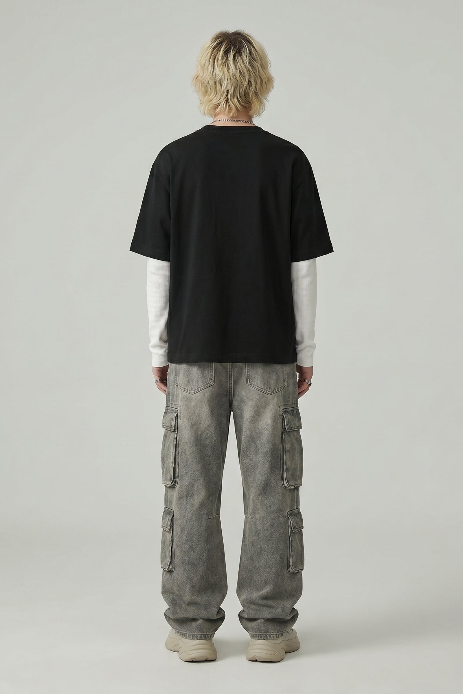 Person wearing a black t-shirt and gray cargo pants on a plain background