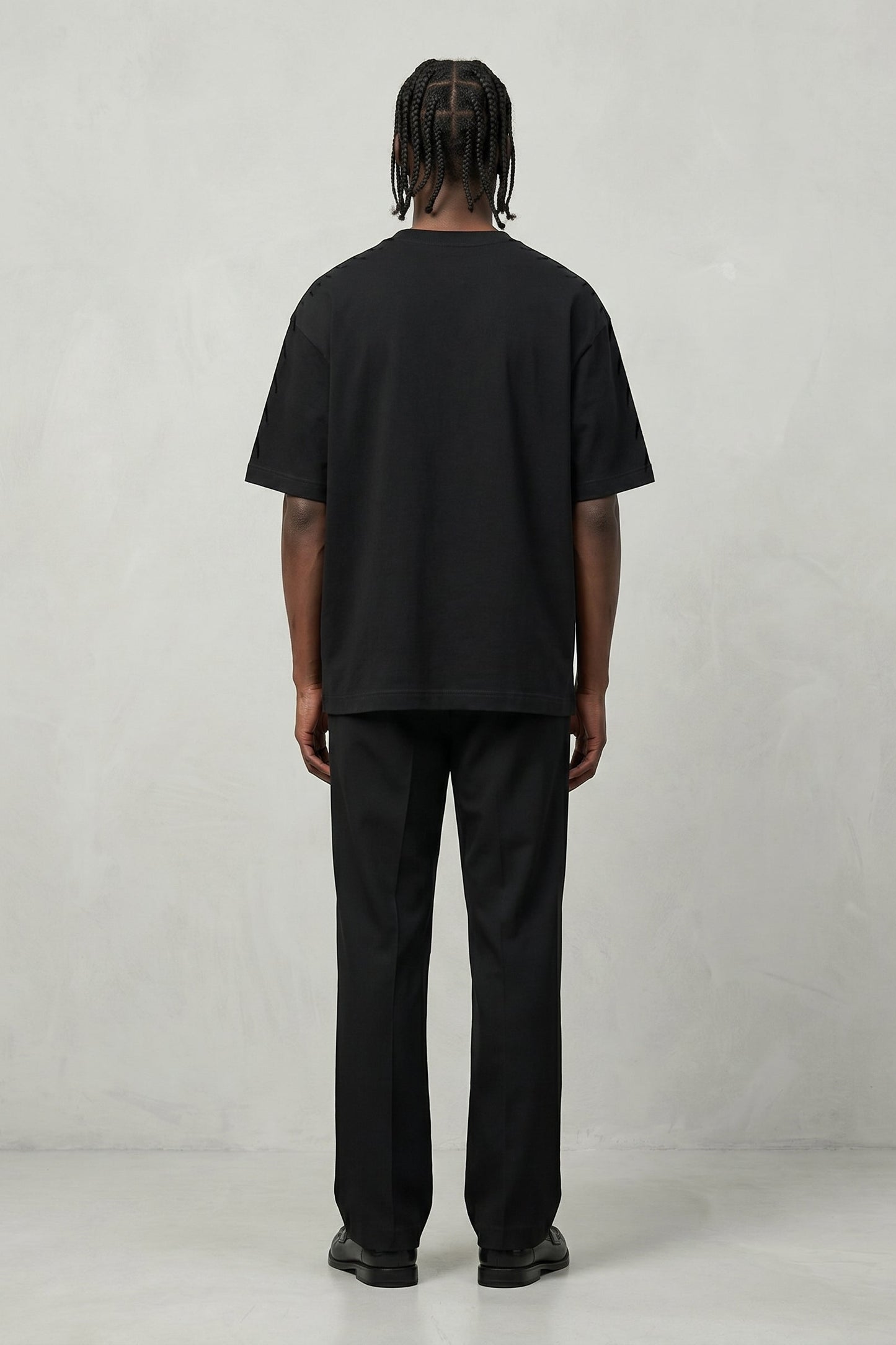 Person wearing a black t-shirt and pants on a plain background