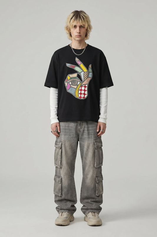 Person wearing a black t-shirt with a colorful graphic design and gray cargo pants on a plain background