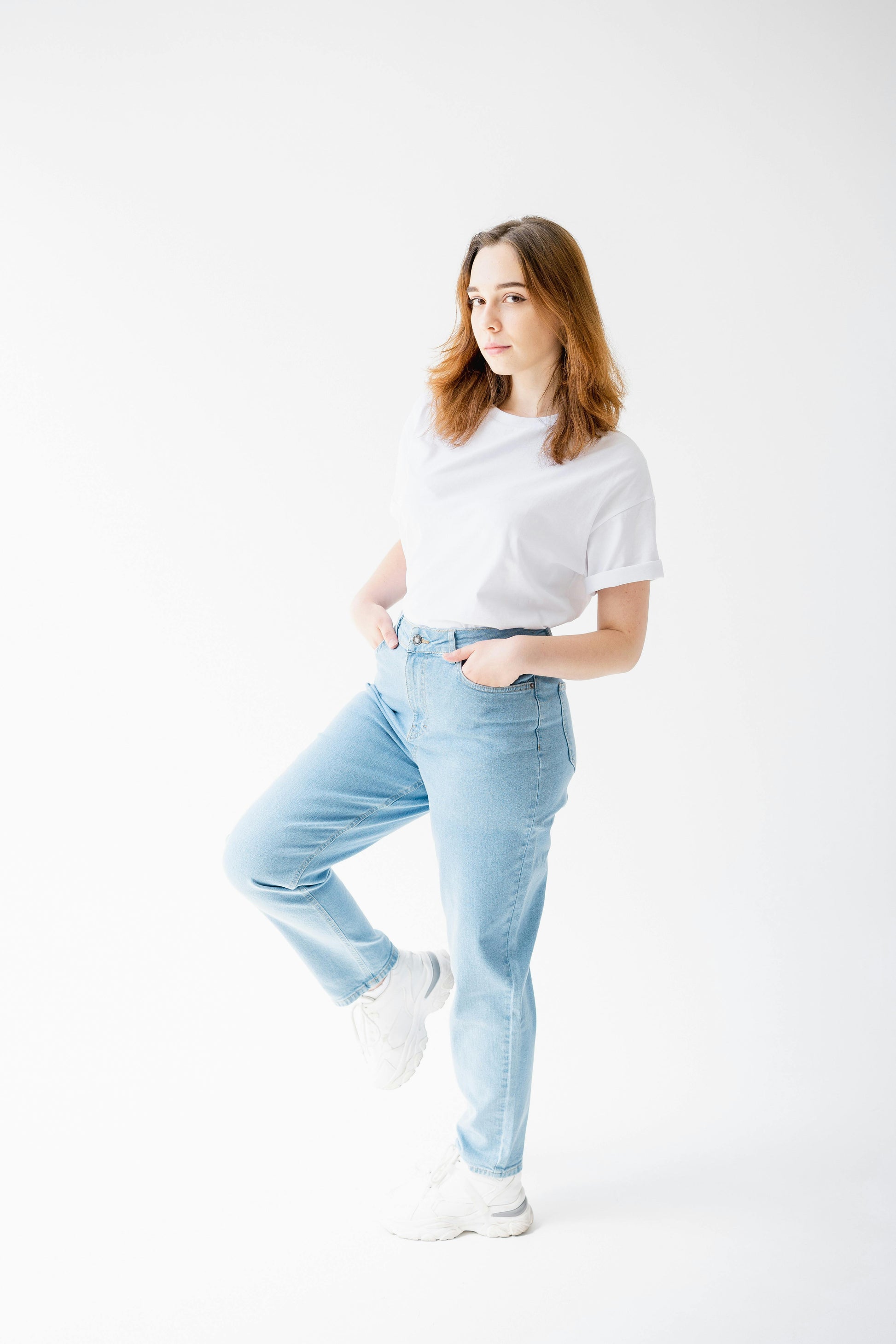 Woman wearing a white t-shirt and light blue jeans on a white background