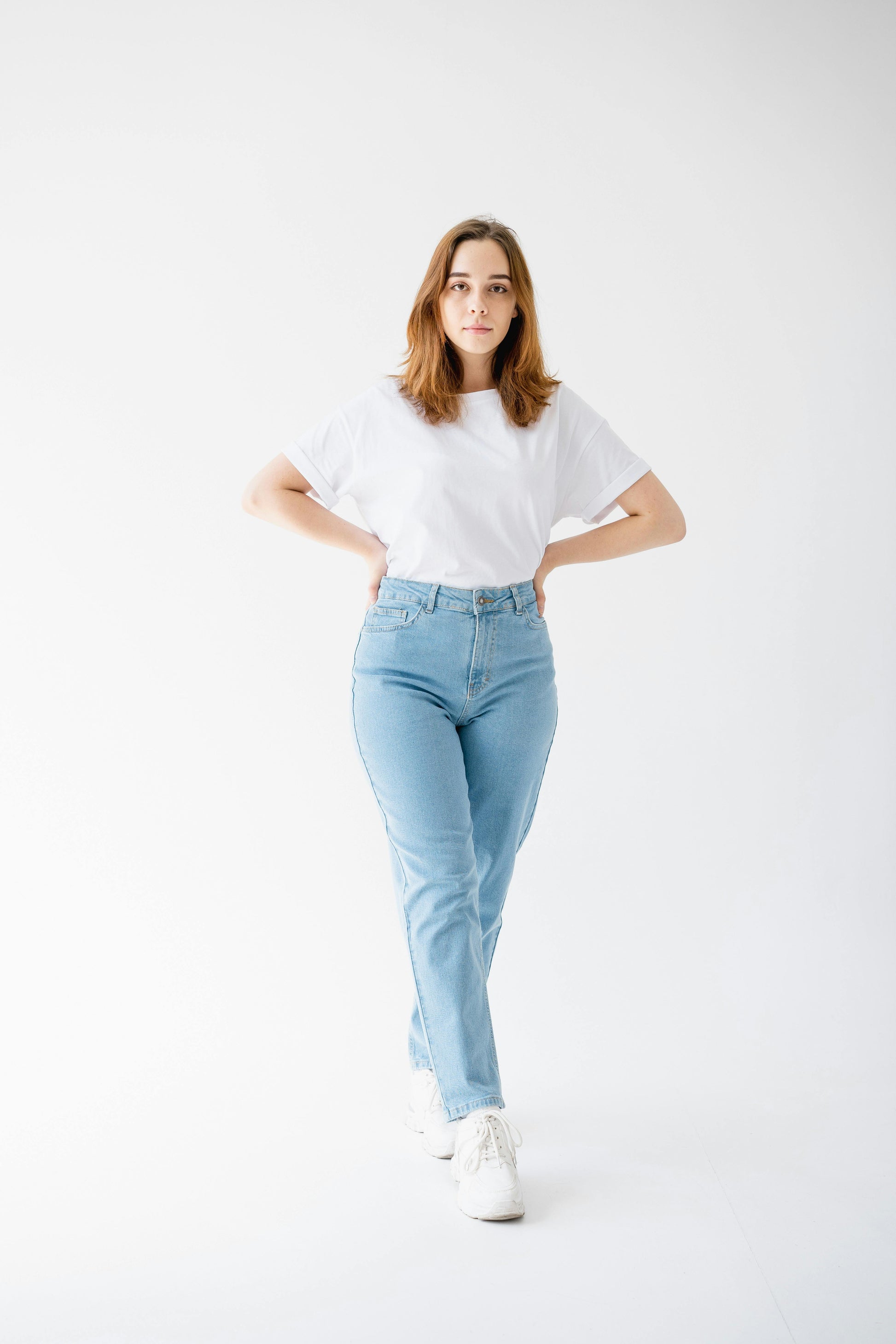 Woman wearing a white t-shirt and light blue jeans on a white background