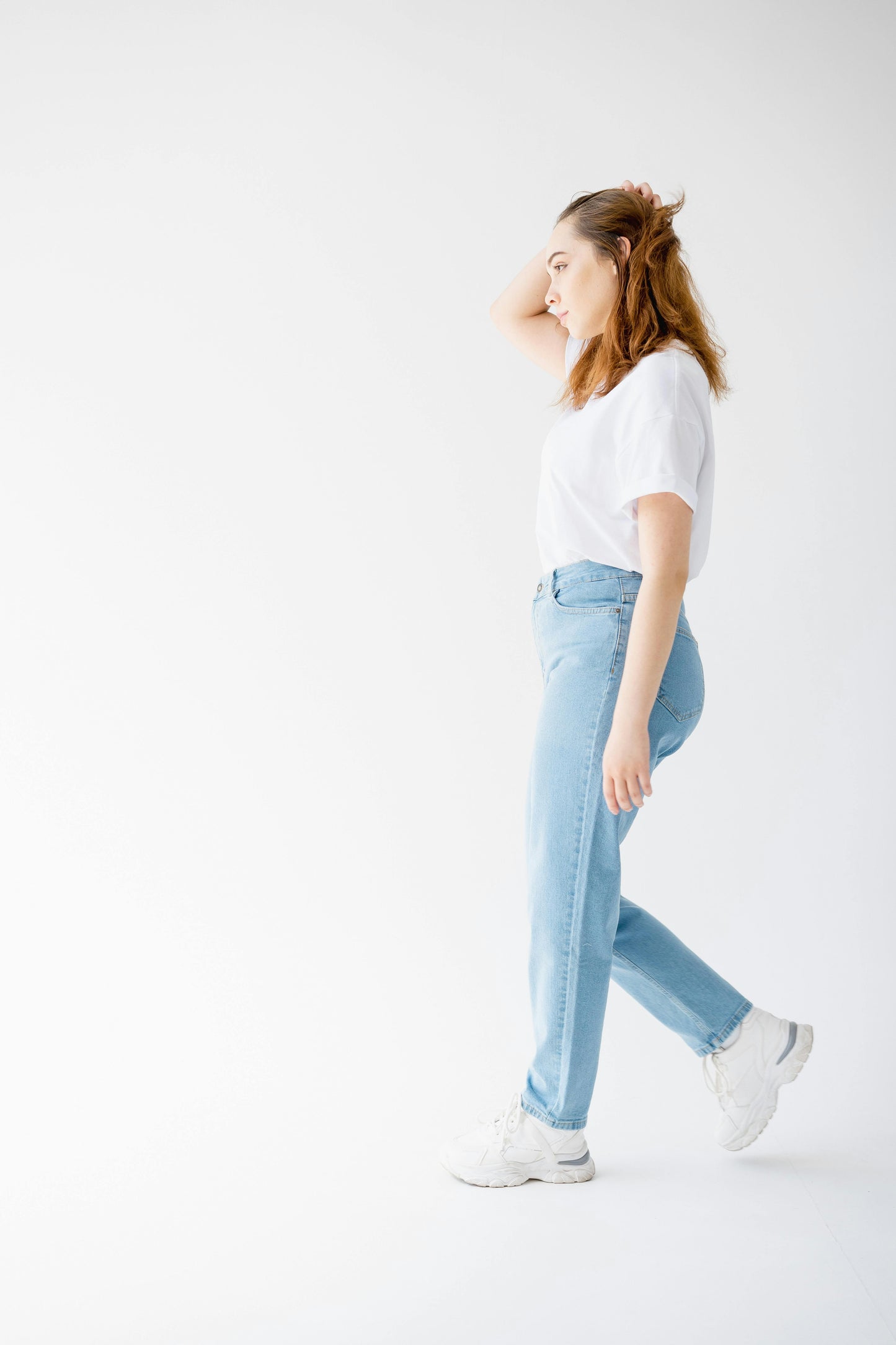 Person wearing light blue jeans and a white shirt on a white background