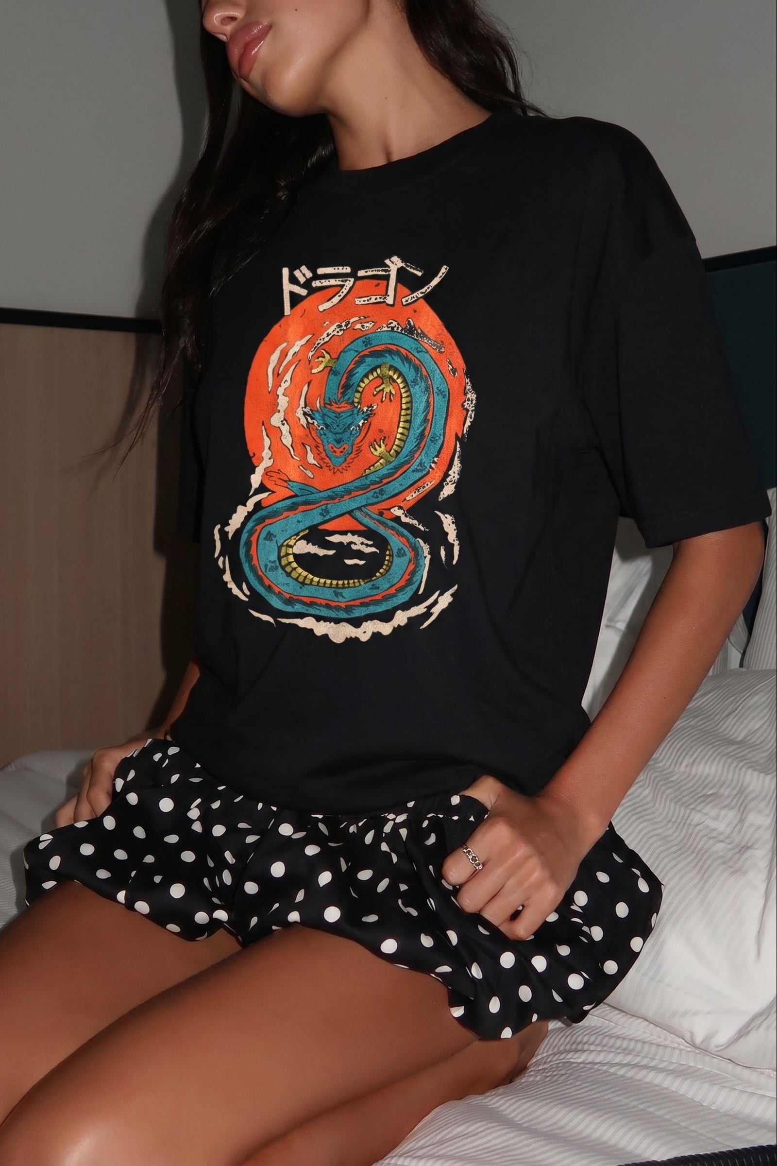 Person wearing a black t-shirt with a colorful dragon design and a polka dot skirt.