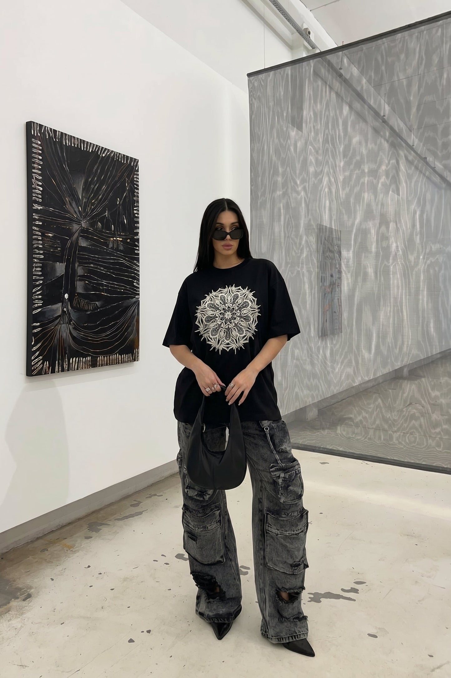 Person wearing a black t-shirt with a white design in an art gallery.