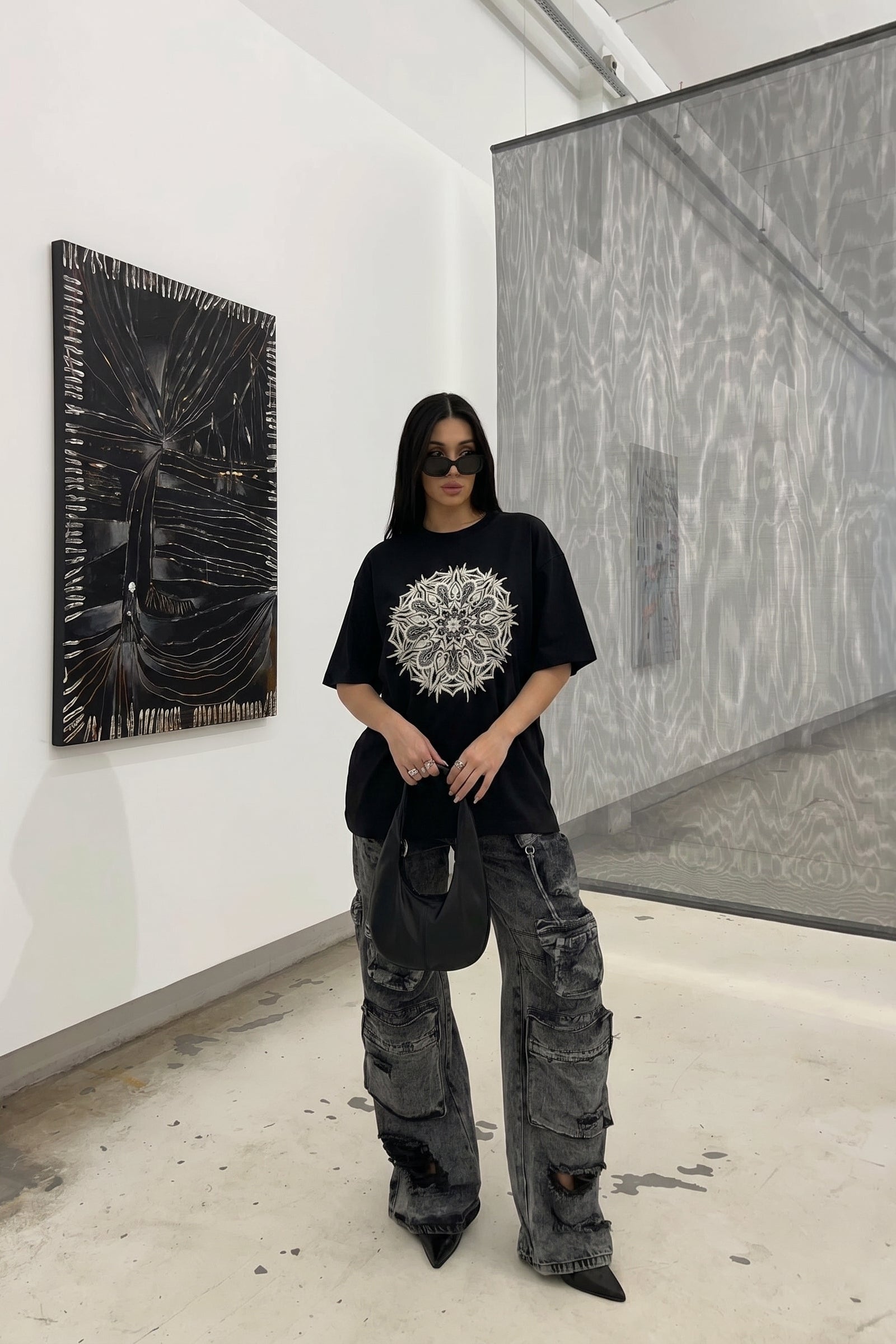 Person wearing a black t-shirt with a white design in an art gallery.
