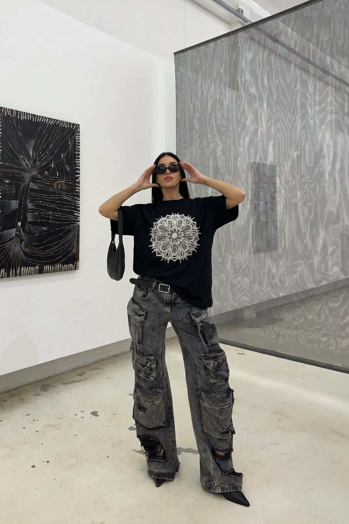 Person wearing a black t-shirt with a white design in an art gallery.