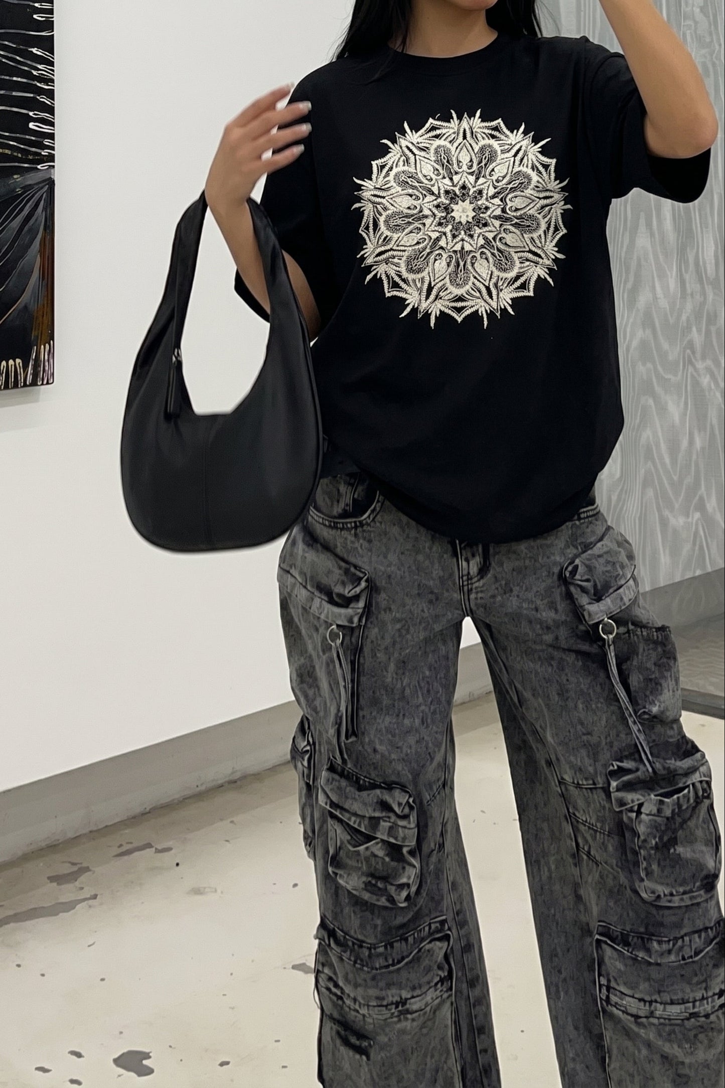 Person wearing a black t-shirt with a white design in an art gallery.