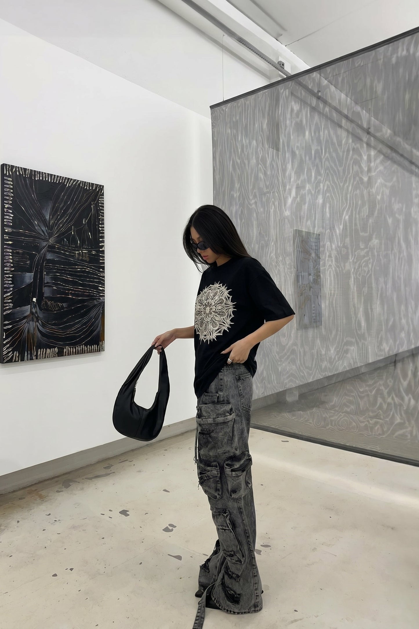 Person wearing a black t-shirt with a white design in an art gallery.